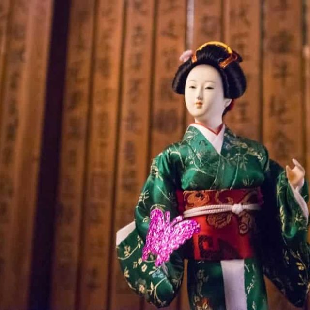 Mannequin en kimono vert et obi rouge dans décor japonais aux murs dorés