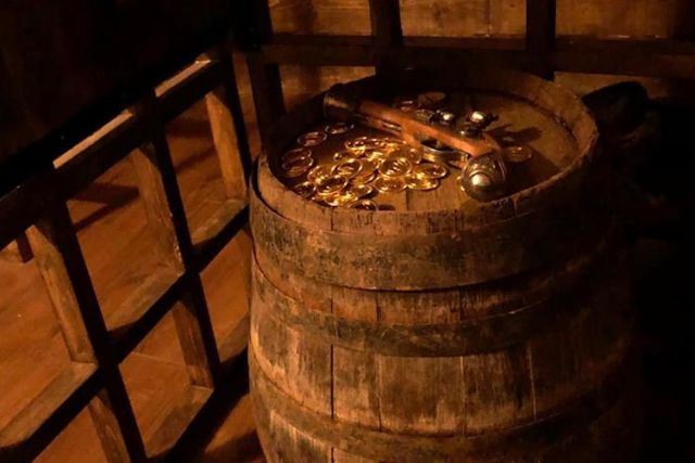 Tonneau rempli de pièces d'or et objets pirates dans une cabine de bateau