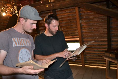 Deux joueurs en casquette lisant des documents dans un grenier de bois, salle Mystère familiale, Musée des Maisons Comtoises
