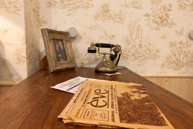 Bureau en bois avec téléphone ancien, cadre doré et vieux journal, salle La Maison Octaverdia