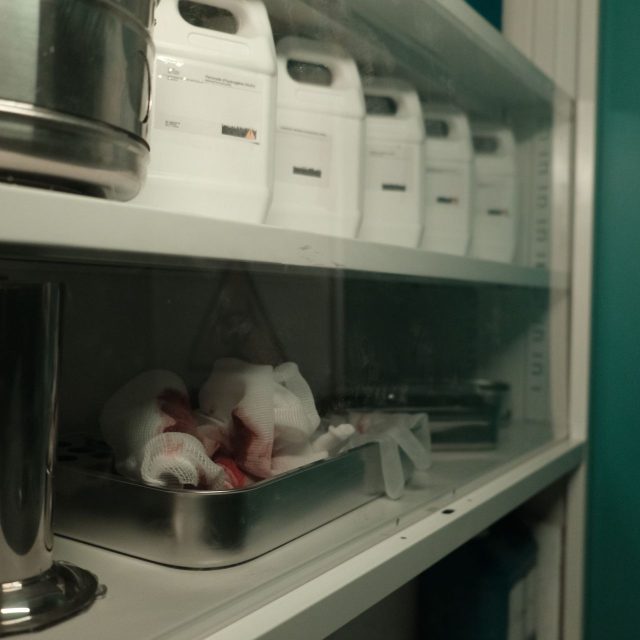 Étagère de laboratoire avec bidons blancs et plateau métallique taché de sang, salle La morgue à Paris