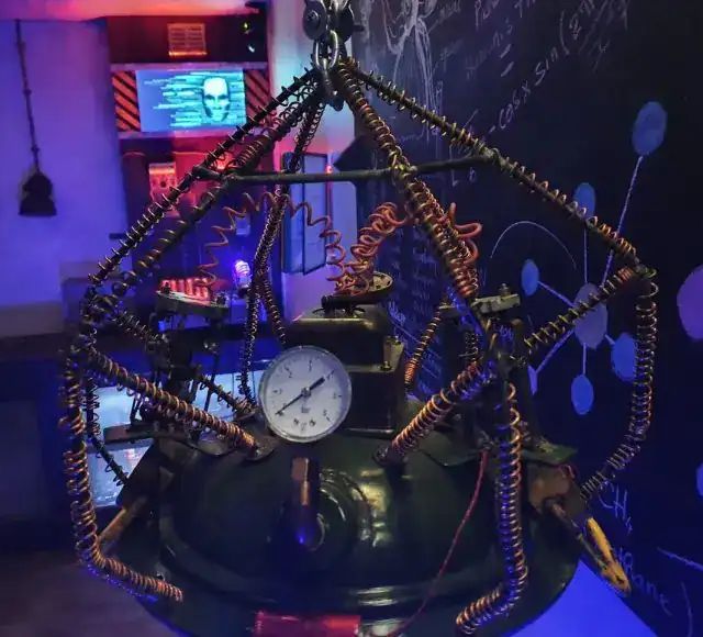 Machine en cuivre dans une cage de fils avec manomètre, éclairage bleu, salle Les fabuleuses inventions du docteur Apfelglück