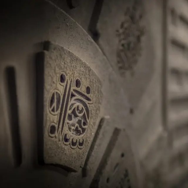 Bas-reliefs de pierre aux motifs géométriques dans la pénombre, salle Projet Omega chez Escape Time à Saint-Herblain