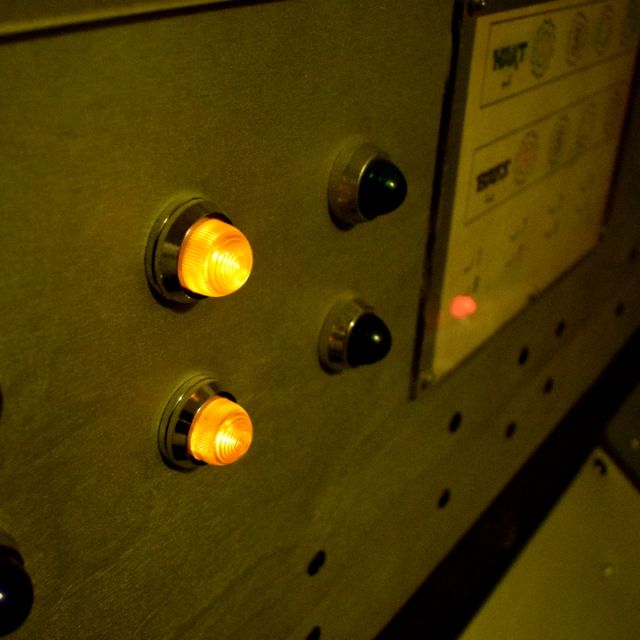Tableau de commande métallique avec boutons orange et cadrans, salle Tchernobyl chez Wood Escape à Locquignol
