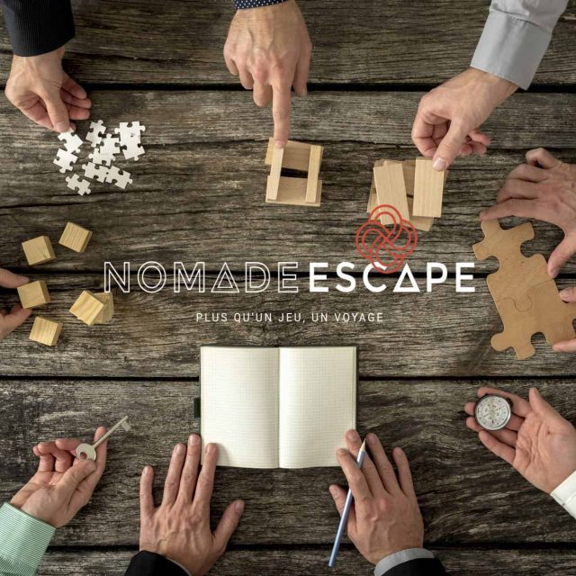 Plusieurs mains autour d'une table manipulent des puzzles et blocs en bois chez Nomade Escape