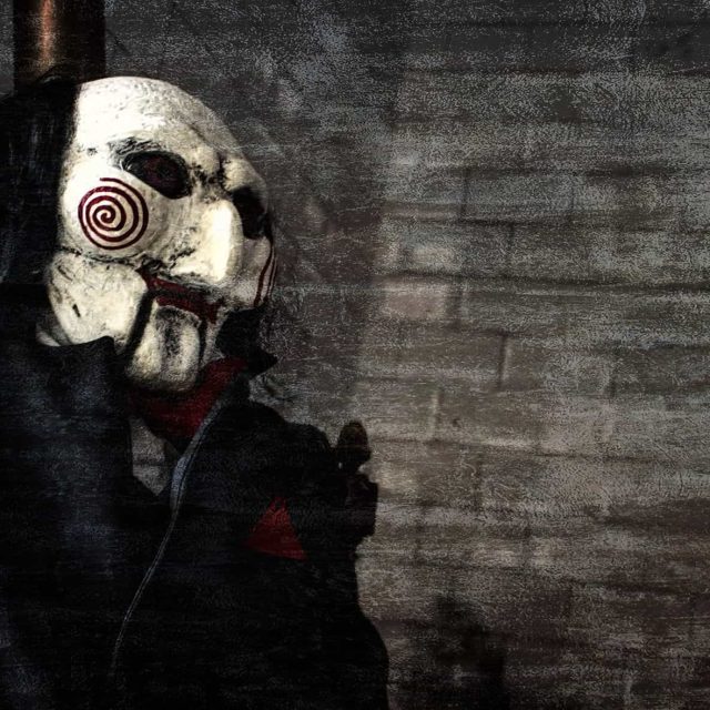 Mannequin au masque blanc spiralé et vêtements noirs dans décor urbain sinistre chez Chambre 237