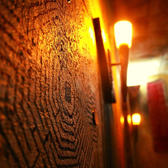 Mur de pierre brute éclairé par des appliques murales chaleureuses dans Le Silence Des Moaï