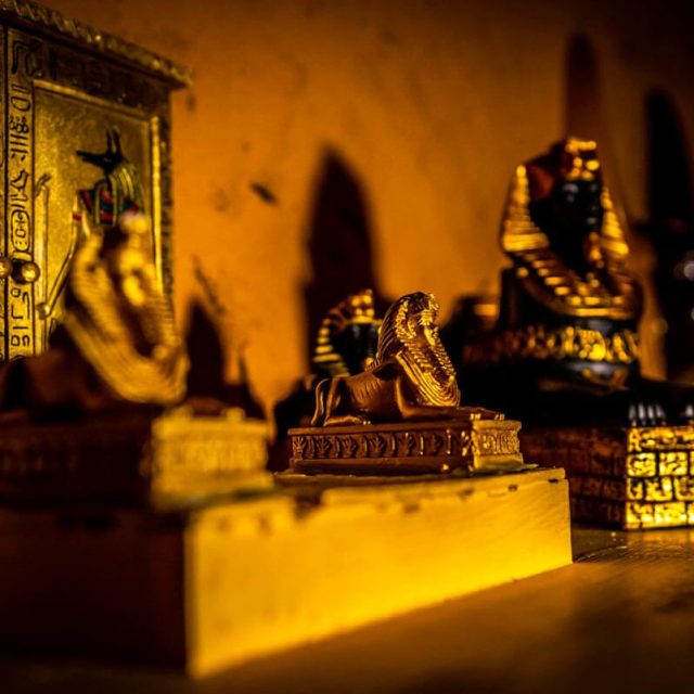 Statuettes et hiéroglyphes égyptiens dorés sous lumière chaude, décor du Tombeau perdu