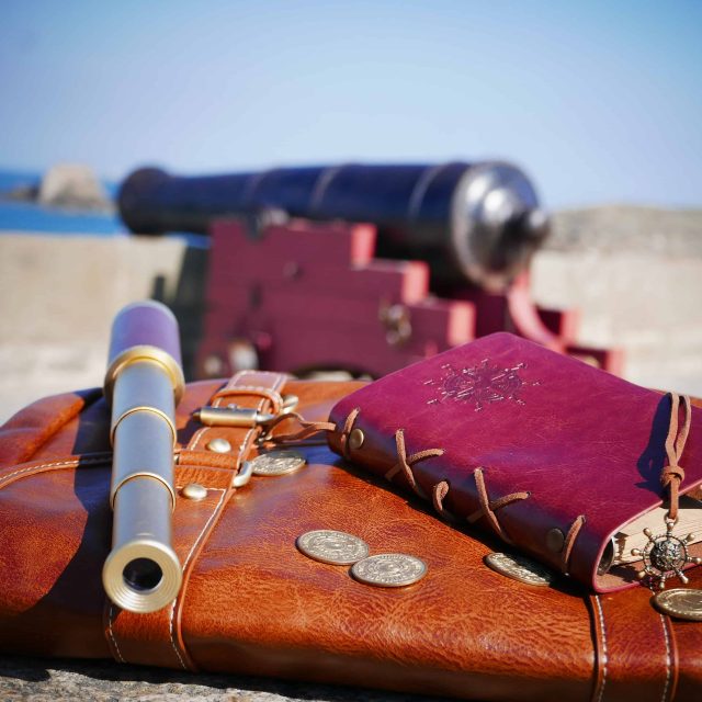 Accessoires de pirate sur plage avec canon en arrière-plan chez Breizh Escape à Dinard