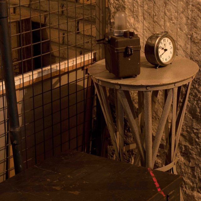 Cellule souterraine avec barreaux, horloge et équipements militaires vintage à Monuments Men