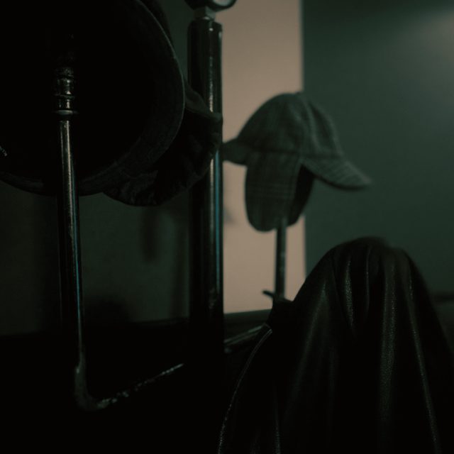Porte-manteau et casquette dans l'ombre d'une pièce sombre, salle Sherlock chez One O'Clock