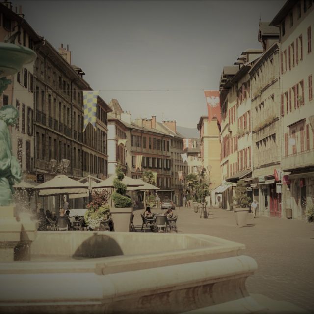 Place de village médiéval avec fontaine, façades colorées et passants en exploration