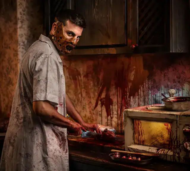 Personnage masqué cuisinant devant un four taché de rouge, salle Le Cannibale