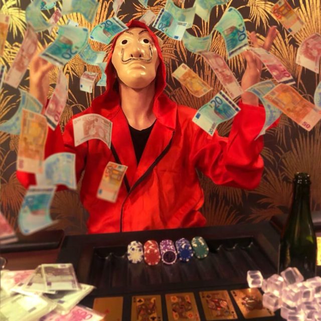 Mannequin en costume rouge entouré de billets, jetons de poker et bouteille de champagne