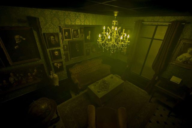 Salon victorien aux murs vert pâle, lustres en cristal et portraits sombres chez Little Red Door Strasbourg