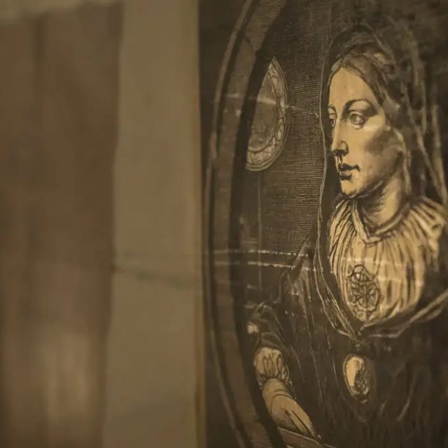 Portrait ovale d'une femme gravé sur un mur de pierre, salle Le donjon de l'alchimiste chez Escape Time à Saint-Herblain