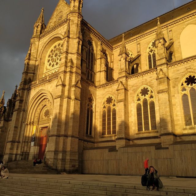 Façade gothique de basilique dorée par le soleil, ciel sombre, salle Le blason au lion d'or chez Hunting Town à Rennes