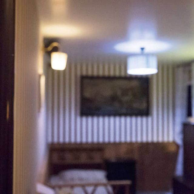 Chambre d'hôtel aux murs rayés vus depuis un couloir, miroir ovale et mur jaune, salle Sunhill Hotel à Saint-Herblain