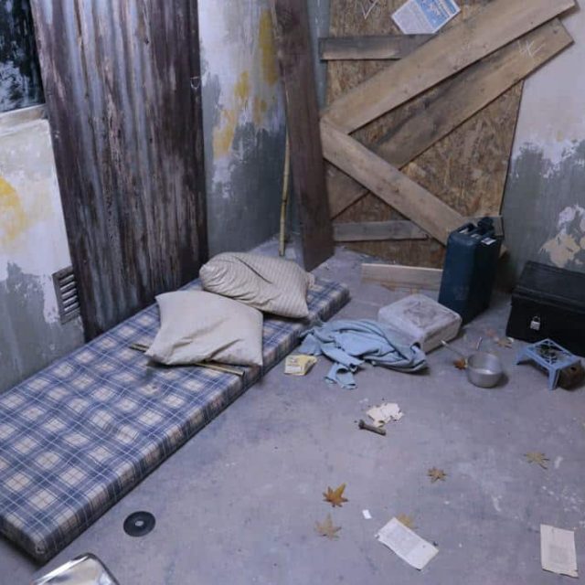 Chambre abandonnée avec lit défait, murs délabres et objets épars dans Zombie motel 2035