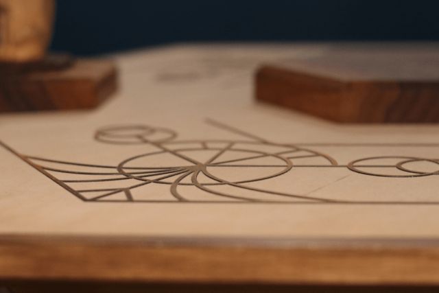 Dessin géométrique complexe gravé sur bois clair, dans La Maison de la Sorcière