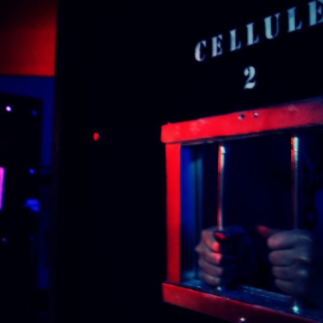 Cellule rouge et bleue avec barreaux, ambiance carcérale chez Escapix à Perpignan