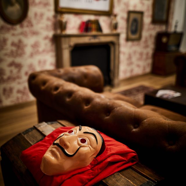 Salon vintage avec canapé marron, cheminée et masque rouge sur table basse chez Closed Strasbourg