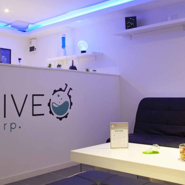 Accueil LIVE Corp. avec logo mural, éclairage bleu, table blanc et canapé noir