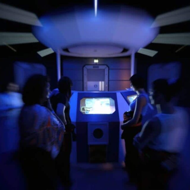 Groupe de joueurs dans une salle futuriste aux lumières bleues avec console interactive chez Winscape à Argenteuil