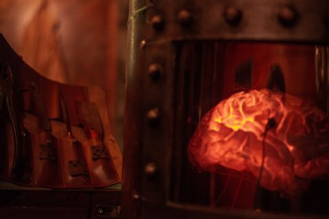 Cerveau lumineux rouge derrière une paroi métallique rivetée, salle Le manoir du Dr Frankenstein chez Alive Room à Bayonne