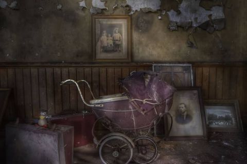 Pièce abandonnée avec landau ancien, portraits fanés et murs décrepits chez Time Out