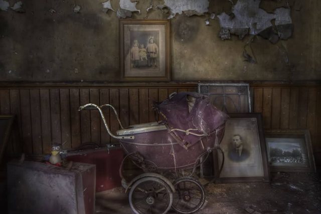 Pièce abandonnée avec landau ancien, portraits fanés et murs décrepits chez Time Out