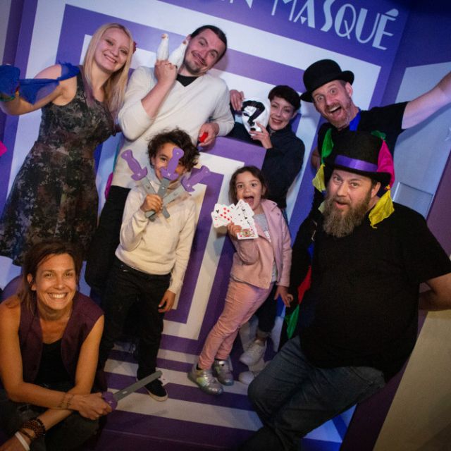 Groupe de joueurs en tenues de magicien posant dans un couloir violet en trompe-l'œil, salle La Grande Illusion, Metz