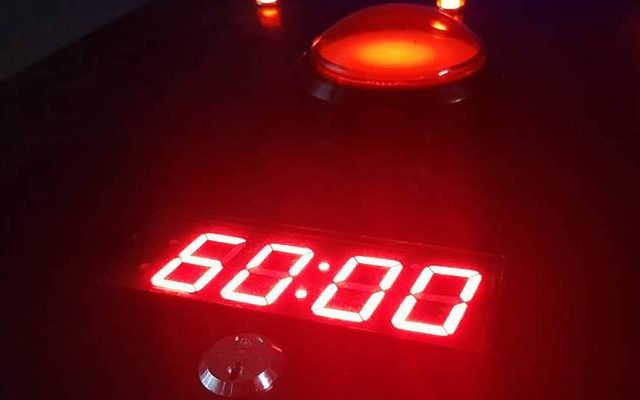 Chronomètre numérique affichant 60:00 sur fond rouge dans la salle Bombe d'Arkham