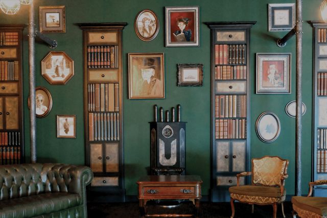 Décor victorien avec murs verts, bibliothèques, portraits et mobilier ancien chez Échappe Toi Si Tu Peux