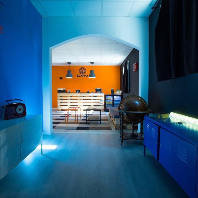 Couloir bleu turquoise avec décor orange, globe terrestre et objets, chez Scappà à Furiani