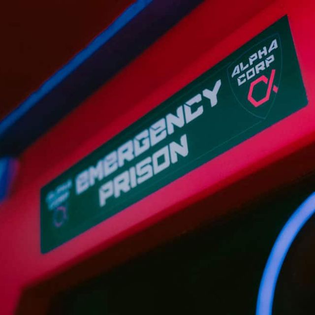 Panneau Emergency Prison sur un décor futuriste rouge et bleu, salle Alpha District chez Escape Time à Mulsanne