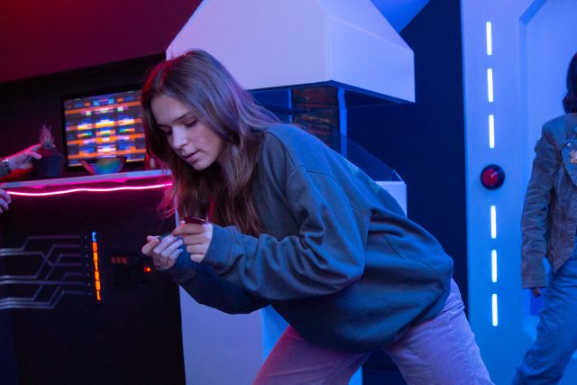 Trois joueurs en tenue décontractée évoluent dans un décor futuriste aux néons bleus et rouges chez Just Escape Lille