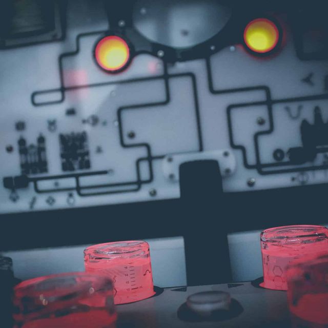 Plaque électronique grise aux circuits tracés et boutons rouges lumineux, salle Dream Machine chez Wake up à Lyon