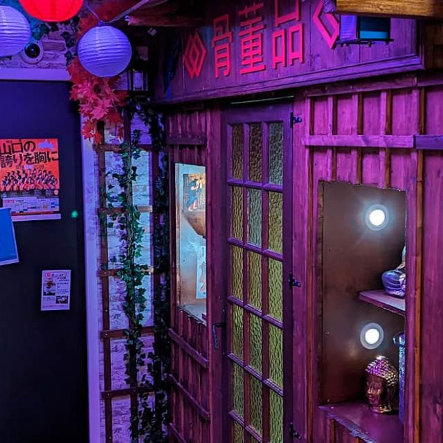 Façade de ruelle japonaise avec fenêtres à croisillons, lampions et affiches, salle Mission Tokyo chez Escape Time à Angers