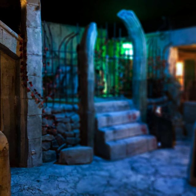 Ruelle nocturne pavée avec colonnes bleues, lampadaires et statues dans Mystère à Lived Street