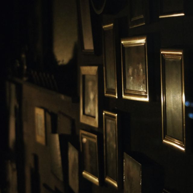Couloir sombre aux murs noirs, cadres dorés éclairés, ambiance furtive dans Opération Tournesol