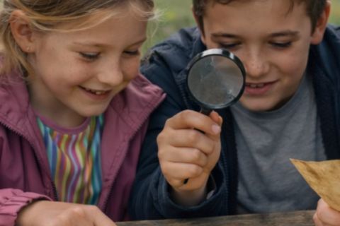Deux enfants examinent une carte à la loupe, jeu Le voleur du Thabor à Rennes