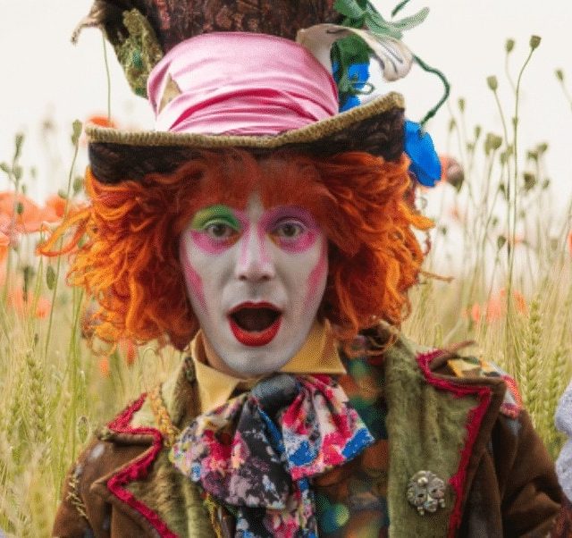 Personnage maquillé aux cheveux roux orange dans un champ de fleurs, Le chapelier fou chez Mind and Run