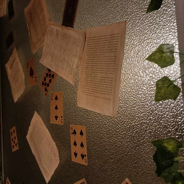 Pages manuscrites, cartes à jouer et végétal sur mur texturé chez Wonderland, Marseille