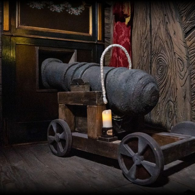 Canon noir sur affût de bois dans une cale sombre, salle Le trésor de Barbe Noire, Time Adventure à Reims