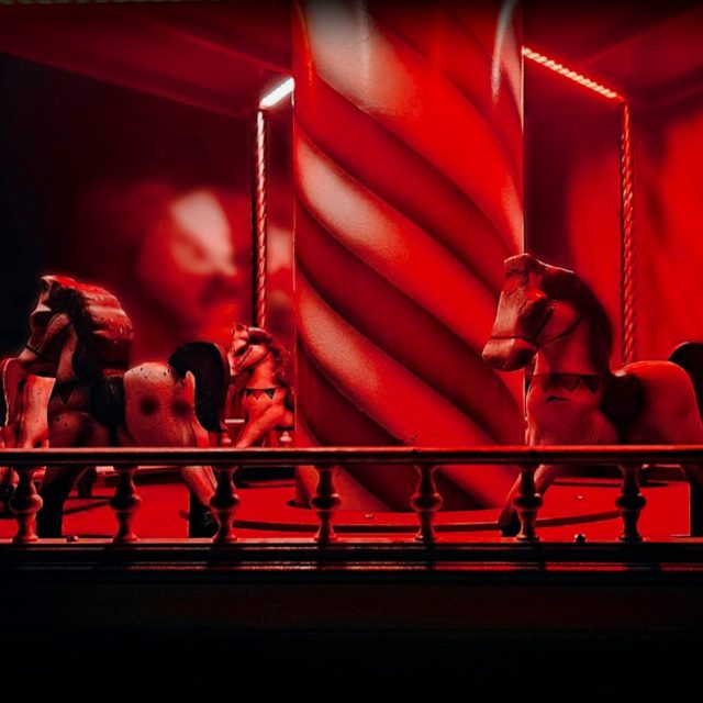 Manège de chevaux de bois sous une lumière rouge, salle Le cirque hanté chez Freeing à Saint-Maximin