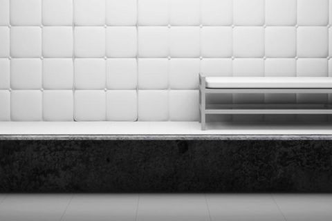 Cellule capitonnée de panneaux blancs avec un banc métallique, en noir et blanc, salle Le patient 12 chez Cinsens à Millau
