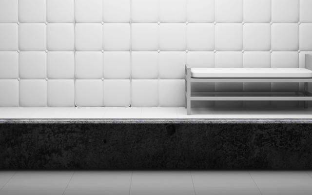 Cellule capitonnée de panneaux blancs avec un banc métallique, en noir et blanc, salle Le patient 12 chez Cinsens à Millau