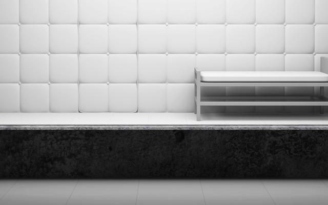 Cellule capitonnée de panneaux blancs avec un banc métallique, en noir et blanc, salle Le patient 12 chez Cinsens à Millau