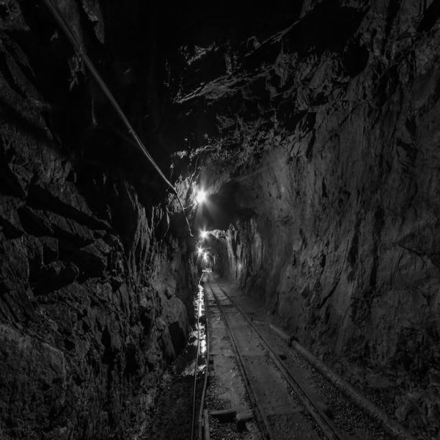 Tunnel de roche éclairé par une lampe lointaine, photo en noir et blanc, salle La mine aux secrets chez Mindtrap